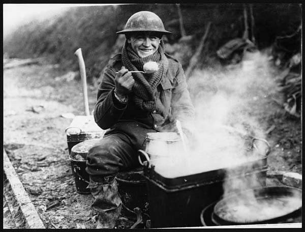Cibo nella Prima guerra mondiale: Soldato dell'Intesa che consuma un pasto mentre è impegnato sul fronte occidentale. Questa immagine è con ogni probabilità una testimonianza dello sforzo propagandistico che i britannici compiono per rassicurare i familiari dei militari impegnati in guerra.