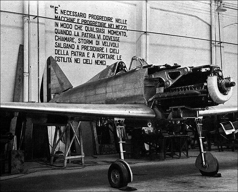 Primo prototipo dell'aereo da caccia RE.2001, prodotto alle Officine Reggiane all'inizio della Seconda guerra mondiale. Dietro l'aereo si nota un proclama di Benito Mussolini - contro la guerra