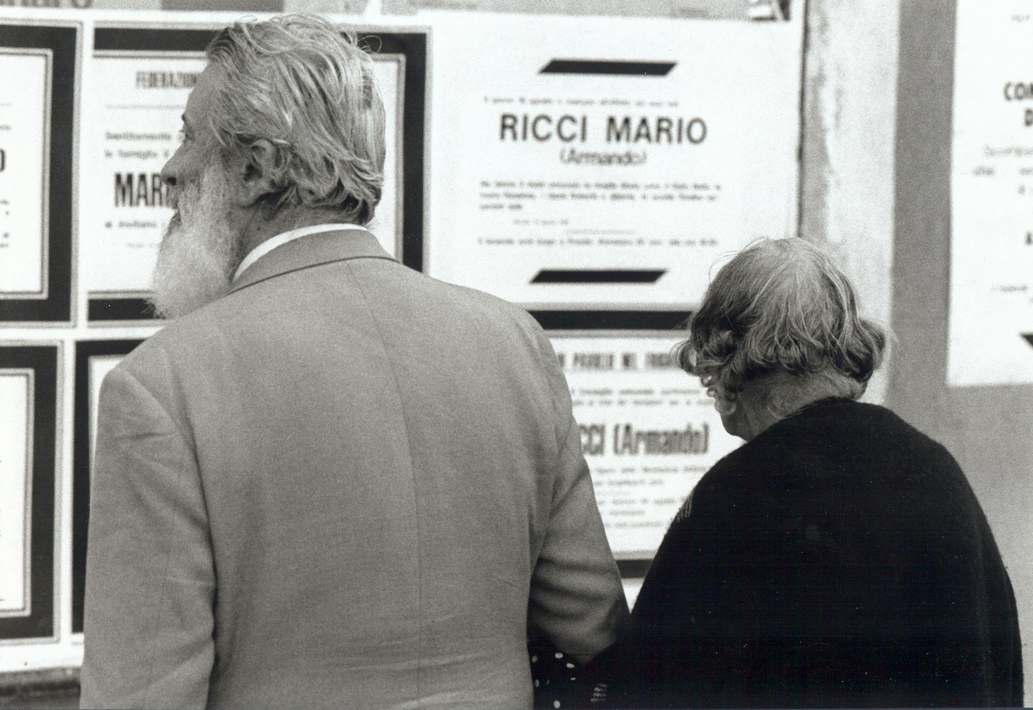 Anziani osservano gli annunci mortuari di Mario Ricci. Foto tratta dalla mostra Mario Ricci "Armando" dal mito alla storia - con Armando nel cuore