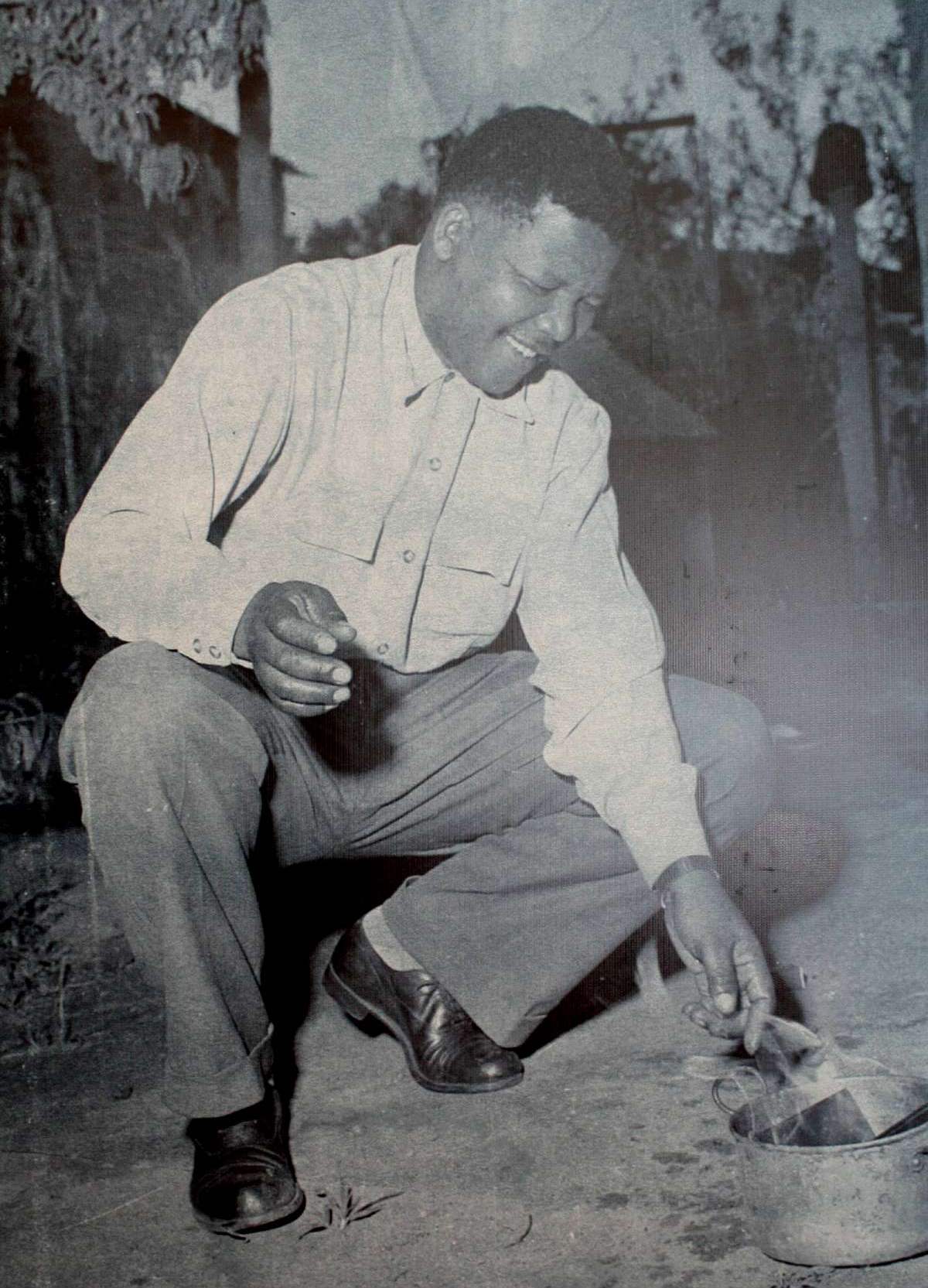 Nelson Mandela nel 1960, ritratto mentre brucia uno dei lasciapassare imposti ai neri dal governo sudafricano dell'apartheid